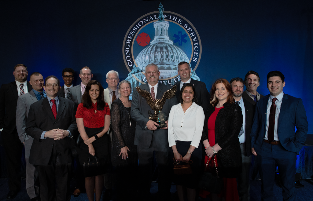 people standing on a stage with one man in the middle holding a trophy