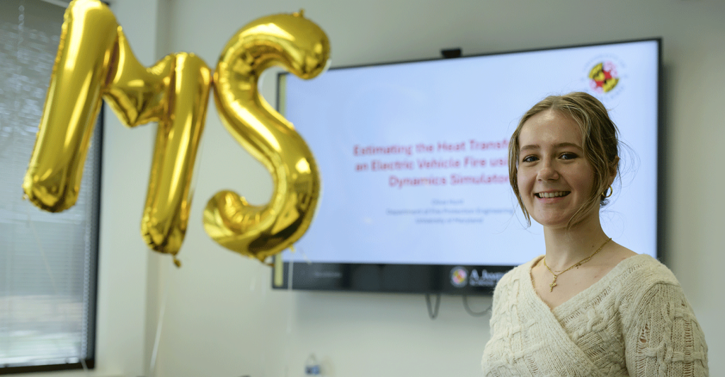 Olivita presenting thesis on electric vehicle fire modeling with MS balloons in background