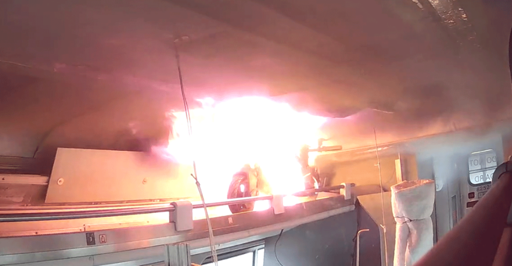 Flames are visible from an e-scooter during an experiment to examine the impact of thermal runaway-initiated e-mobility device fires on a passenger railcar